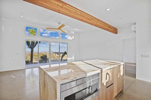 kitchen featuring ceiling fan, light brown cabinetry, built in microwave, beam ceiling, and a center island