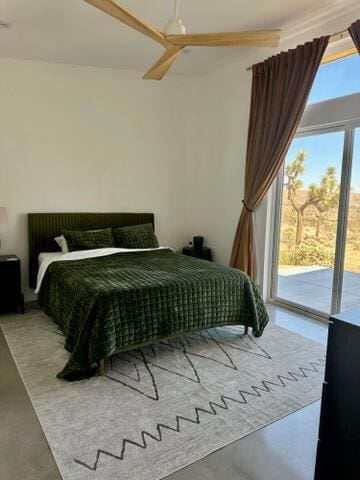 bedroom with ceiling fan, concrete flooring, and access to outside