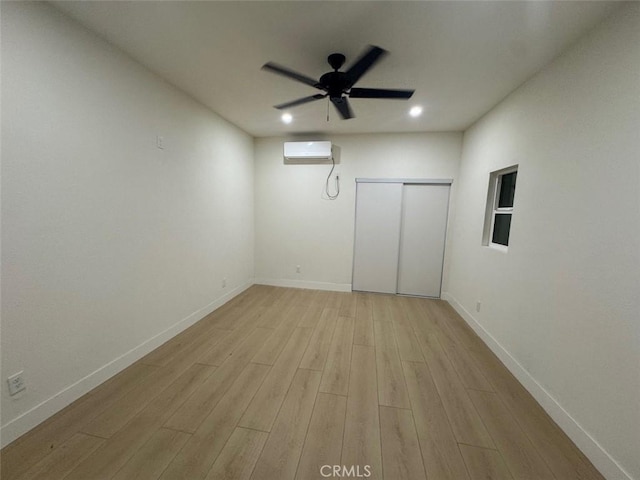 empty room featuring light wood-type flooring, ceiling fan, and an AC wall unit