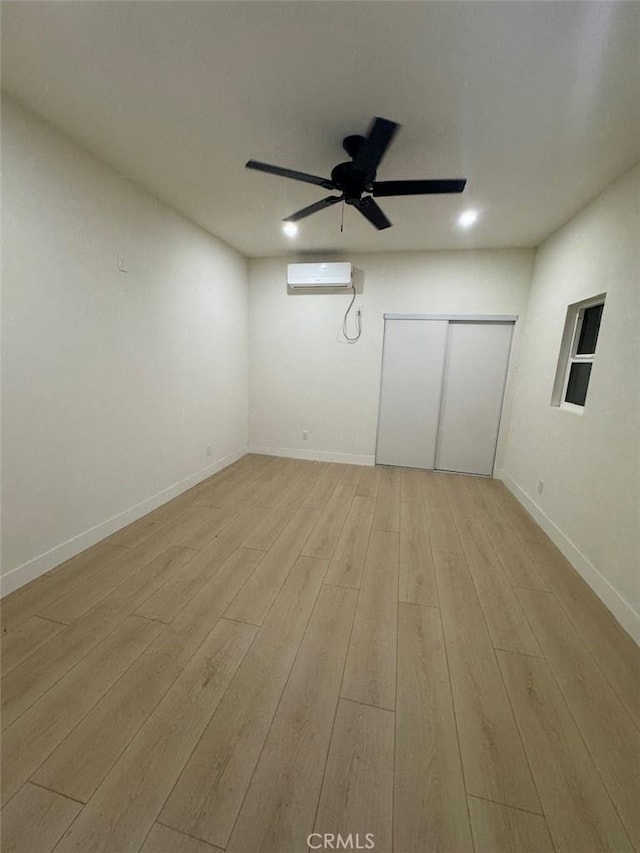 unfurnished room featuring light wood-type flooring and a wall mounted air conditioner