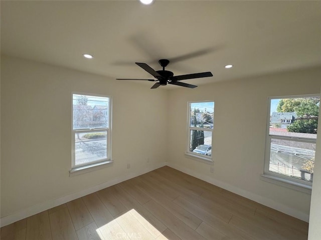 unfurnished room featuring ceiling fan, a wealth of natural light, and light hardwood / wood-style flooring