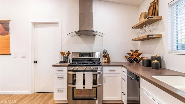 kitchen with appliances with stainless steel finishes, light hardwood / wood-style flooring, white cabinetry, and exhaust hood