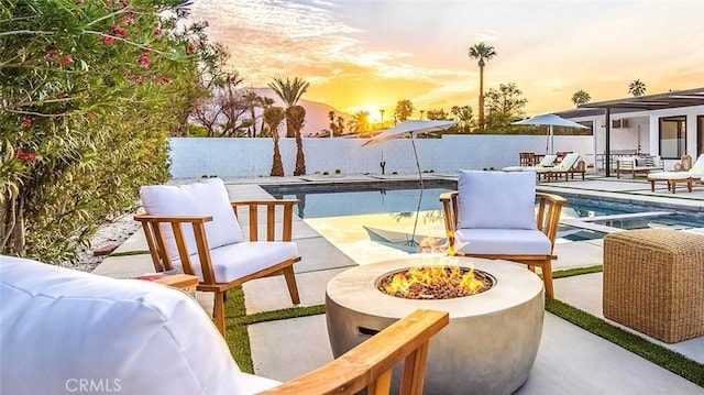 patio terrace at dusk featuring a fenced in pool and an outdoor fire pit