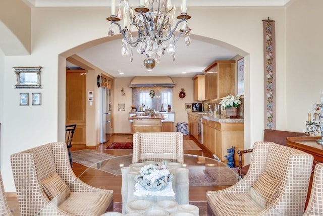 dining area with light wood-type flooring, sink, and an inviting chandelier