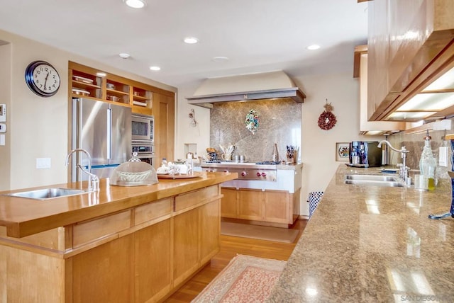 kitchen featuring sink, light wood-type flooring, backsplash, and appliances with stainless steel finishes