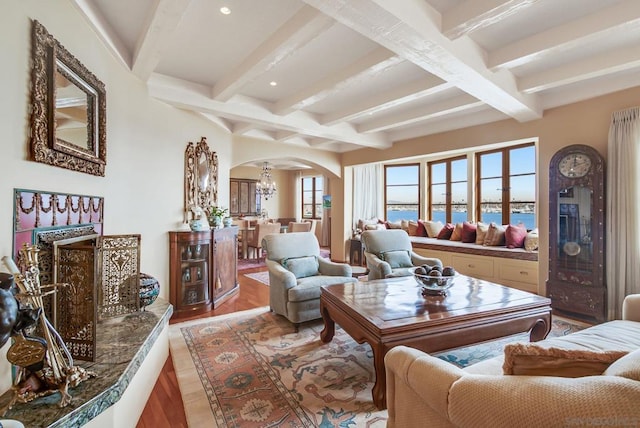 living room featuring plenty of natural light, beam ceiling, a water view, and light hardwood / wood-style flooring