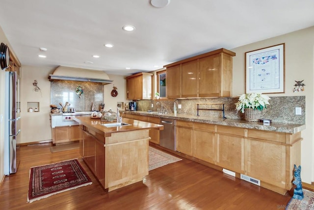 kitchen with backsplash, exhaust hood, a kitchen island, dark hardwood / wood-style flooring, and stainless steel appliances