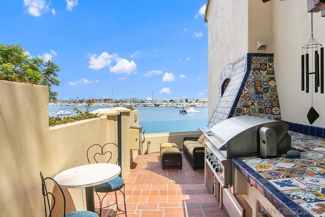 view of patio with a grill and a water view