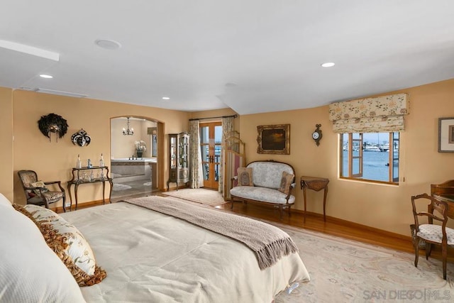 bedroom with light wood-type flooring, an inviting chandelier, and multiple windows