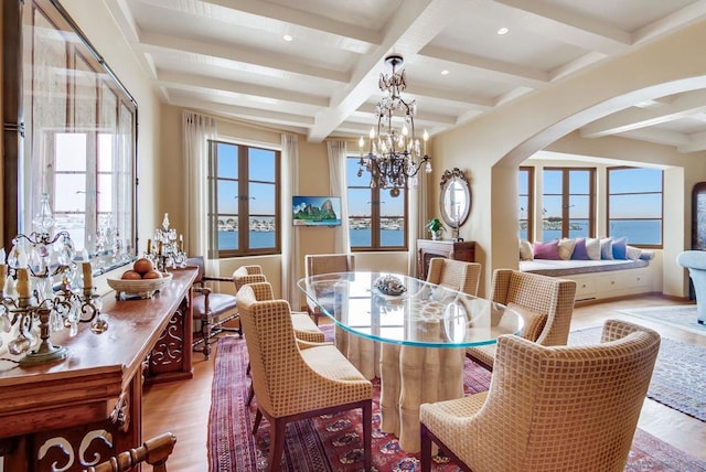 dining room with beam ceiling, a water view, wood-type flooring, and coffered ceiling