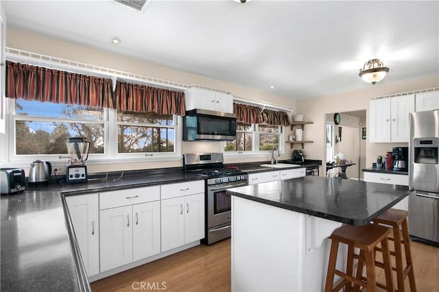 kitchen featuring appliances with stainless steel finishes, white cabinetry, light hardwood / wood-style flooring, and sink