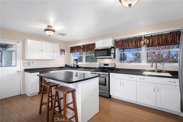 kitchen featuring white cabinets, appliances with stainless steel finishes, a kitchen island, and sink