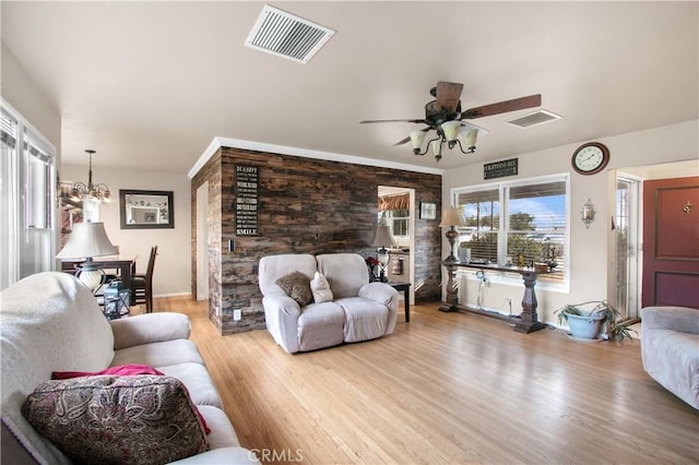 living room with ceiling fan with notable chandelier and light wood-type flooring