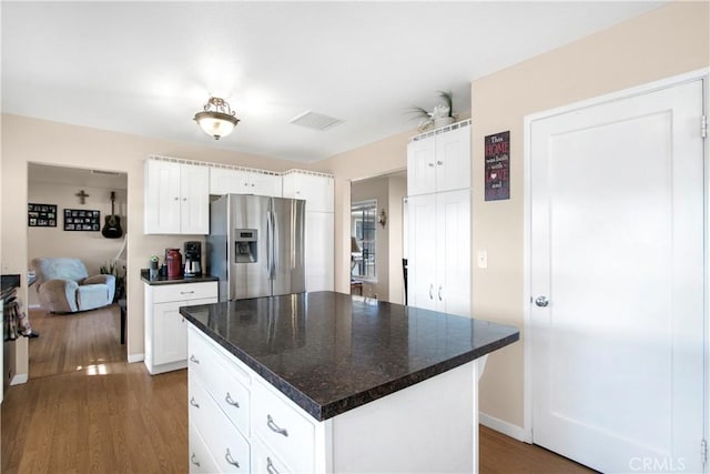 kitchen featuring dark hardwood / wood-style flooring, dark stone countertops, stainless steel fridge with ice dispenser, a center island, and white cabinetry