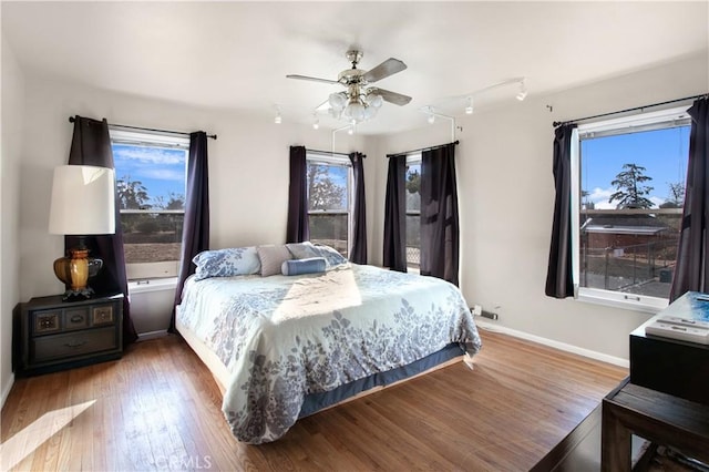 bedroom featuring hardwood / wood-style floors, ceiling fan, and multiple windows