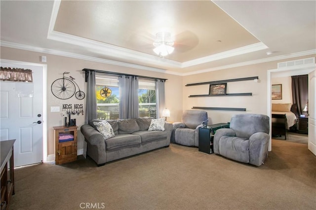 carpeted living room with ceiling fan, crown molding, and a tray ceiling