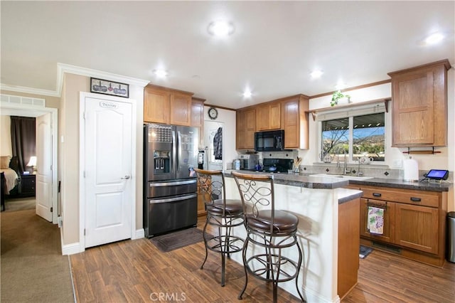 kitchen with a center island, sink, a kitchen breakfast bar, dark hardwood / wood-style flooring, and black appliances