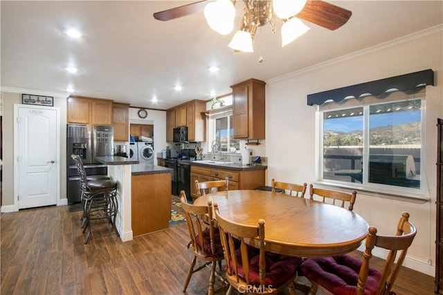 dining area with ceiling fan, dark hardwood / wood-style flooring, separate washer and dryer, and crown molding