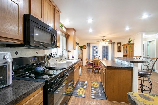 kitchen with black appliances, a center island, a kitchen bar, and light wood-type flooring