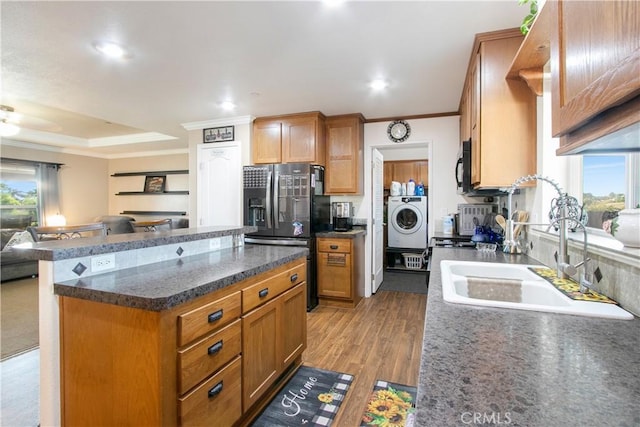 kitchen with stainless steel refrigerator with ice dispenser, washer / dryer, a center island, and plenty of natural light