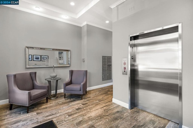 sitting room featuring hardwood / wood-style flooring, ornamental molding, and elevator