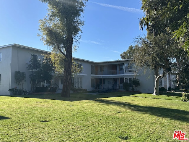 rear view of house featuring a yard and a balcony