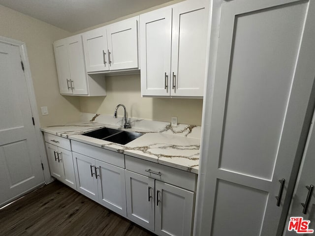 kitchen featuring white cabinetry, sink, light stone counters, and dark hardwood / wood-style floors