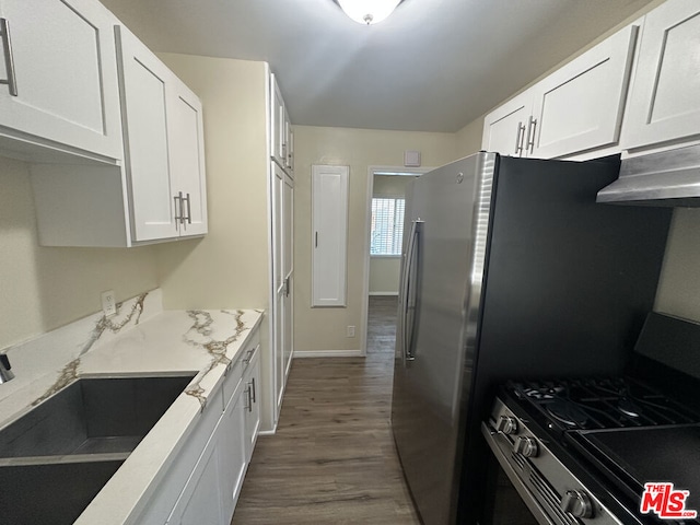 kitchen with white cabinets, light stone counters, stainless steel gas range oven, and dark wood-type flooring