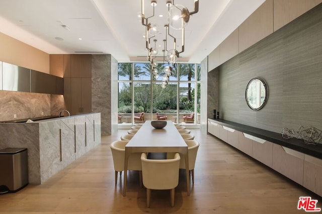 unfurnished dining area with floor to ceiling windows, a chandelier, and light hardwood / wood-style floors