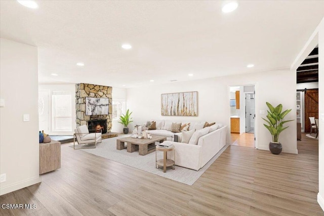 living room featuring a barn door, a fireplace, and light hardwood / wood-style flooring