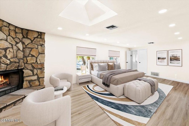 bedroom with light hardwood / wood-style floors and a fireplace