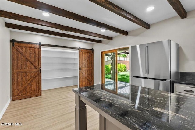 kitchen featuring a barn door, stainless steel fridge, beamed ceiling, and light hardwood / wood-style floors