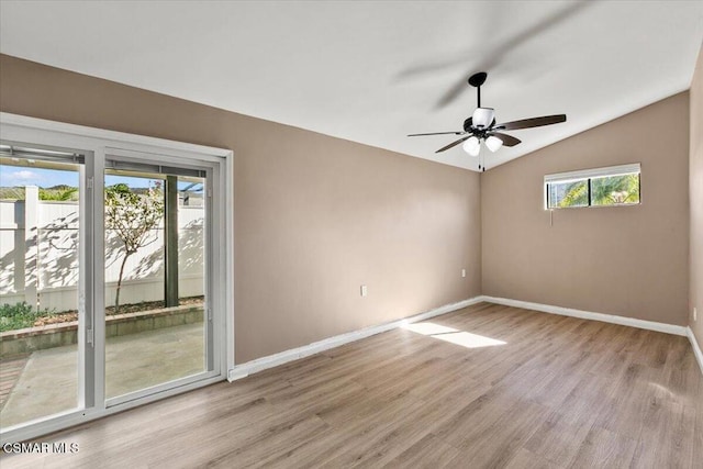 empty room featuring a wealth of natural light, ceiling fan, vaulted ceiling, and light wood-type flooring