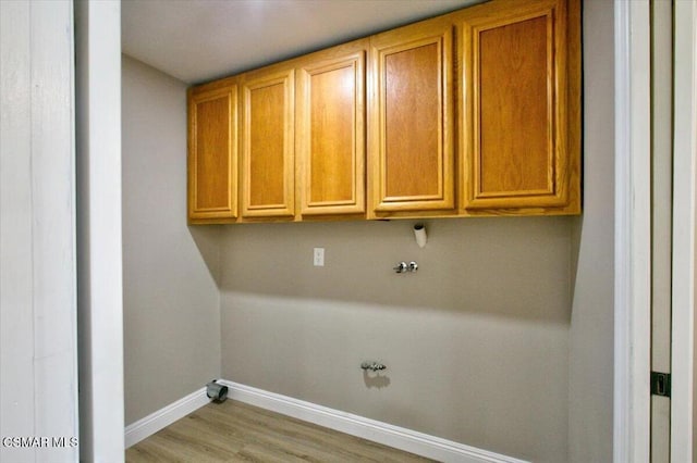 clothes washing area featuring hookup for a gas dryer, light hardwood / wood-style flooring, and cabinets