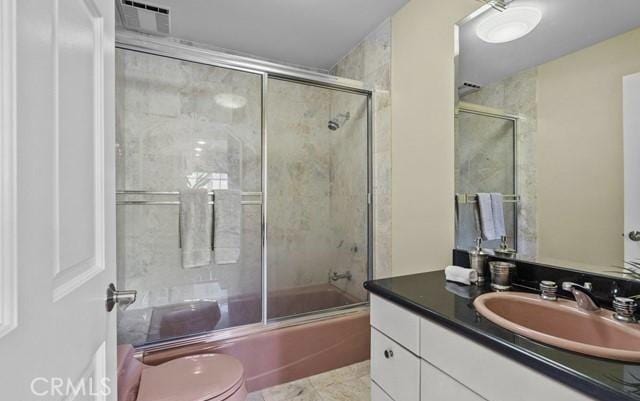 full bathroom featuring enclosed tub / shower combo, vanity, and toilet