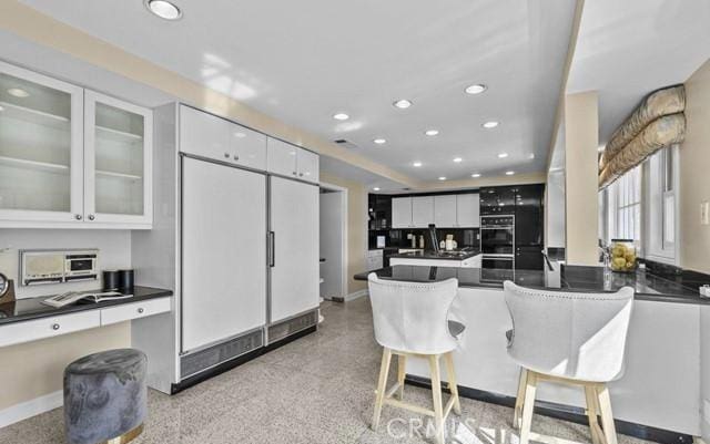 kitchen with black double oven, refrigerator, and white cabinets