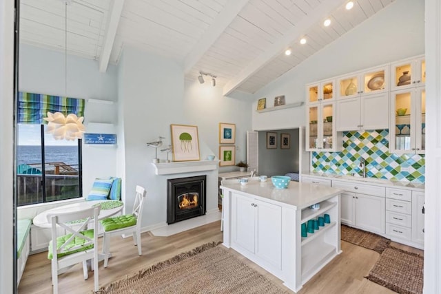 kitchen featuring tasteful backsplash, white cabinetry, a water view, light hardwood / wood-style flooring, and a kitchen island