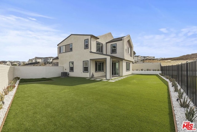 rear view of house featuring central AC and a lawn