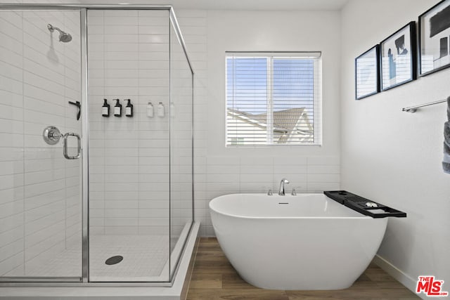 bathroom featuring wood-type flooring, separate shower and tub, and tile walls