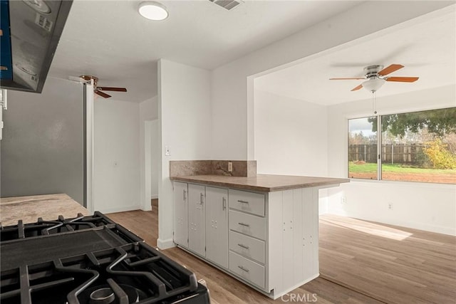 kitchen featuring ceiling fan, white cabinets, kitchen peninsula, light hardwood / wood-style floors, and black range