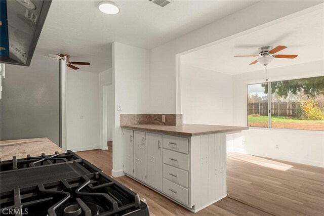 5690 Paradise Ave, Paradise, CA 95969 - kitchen featuring a ceiling fan, black gas stove, light wood finished floors, and a peninsula