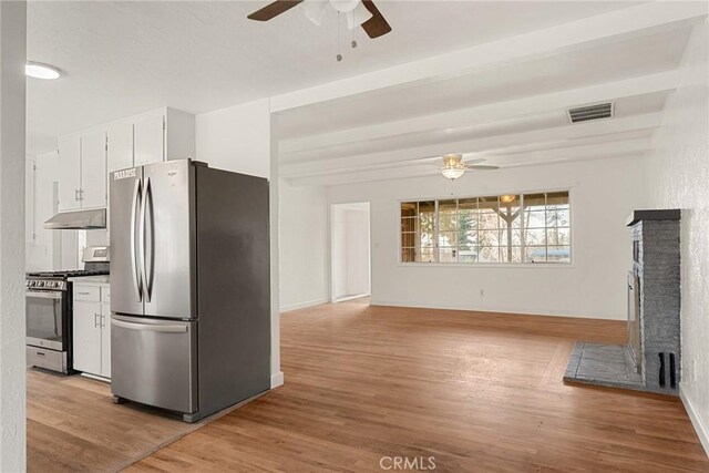 kitchen featuring ceiling fan, appliances with stainless steel finishes, beamed ceiling, light hardwood / wood-style floors, and white cabinetry