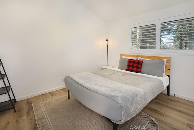 bedroom featuring wood-type flooring and vaulted ceiling