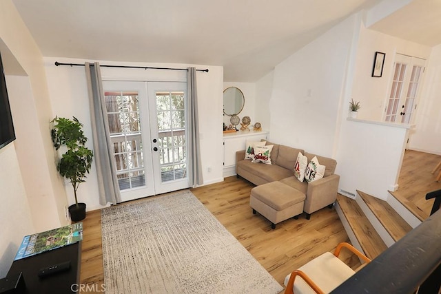 sitting room with french doors, light hardwood / wood-style flooring, and lofted ceiling