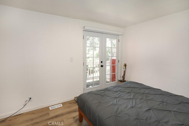 bedroom with access to exterior, hardwood / wood-style floors, and french doors