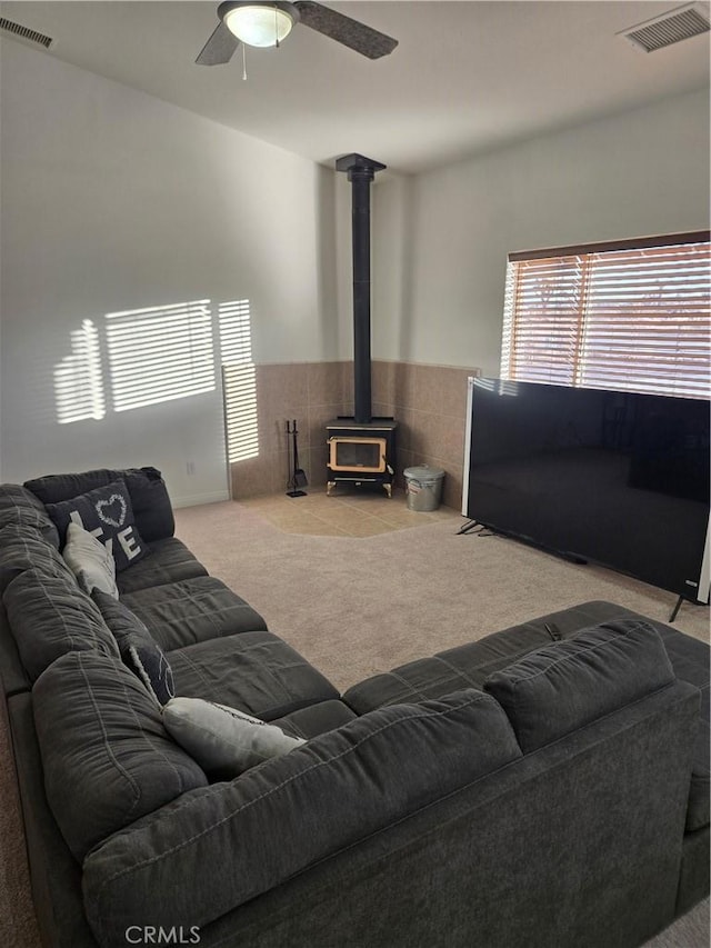 living room with carpet floors, a wood stove, and ceiling fan