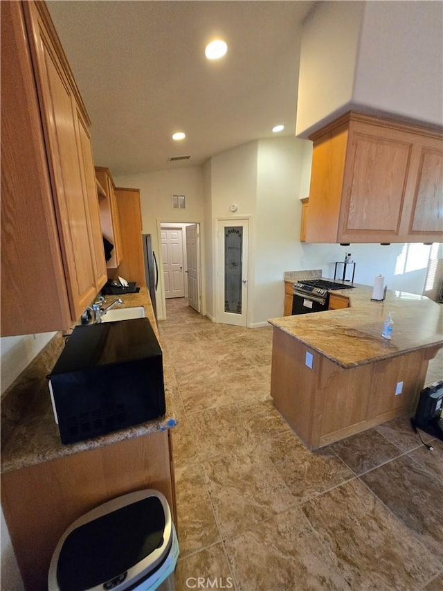 kitchen with appliances with stainless steel finishes, sink, lofted ceiling, and kitchen peninsula