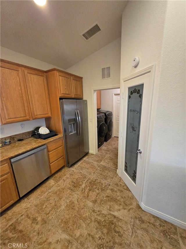 kitchen with independent washer and dryer, stainless steel appliances, and lofted ceiling