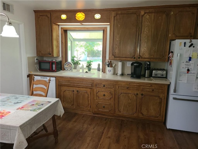 kitchen featuring decorative light fixtures, sink, dark hardwood / wood-style floors, and white appliances