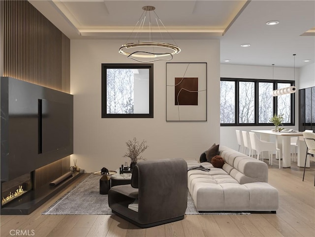 living room featuring a raised ceiling and light wood-type flooring